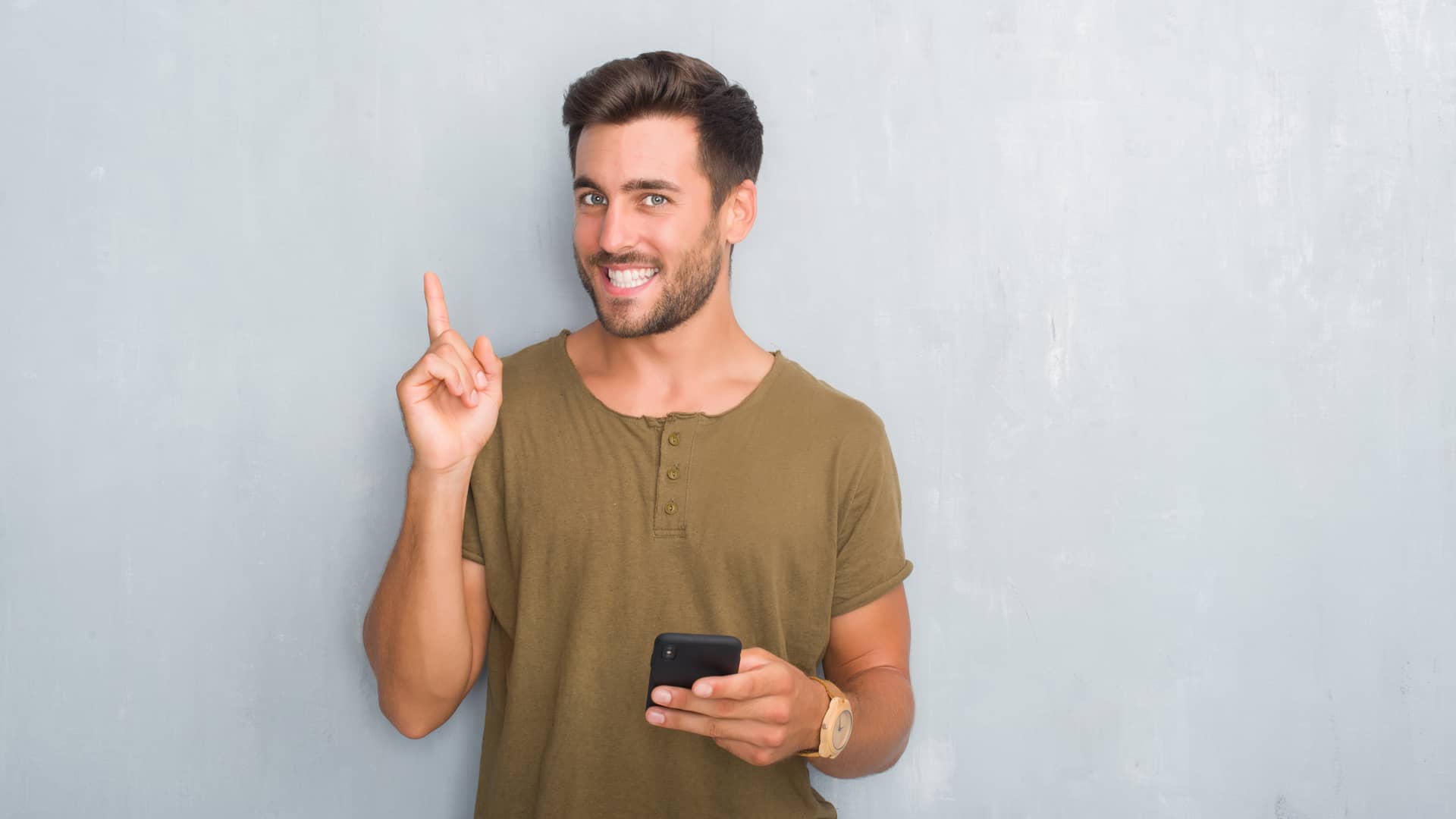 Hombre sonriente al descubrir en su smartphone como empezar a inveritr en criptomonedas