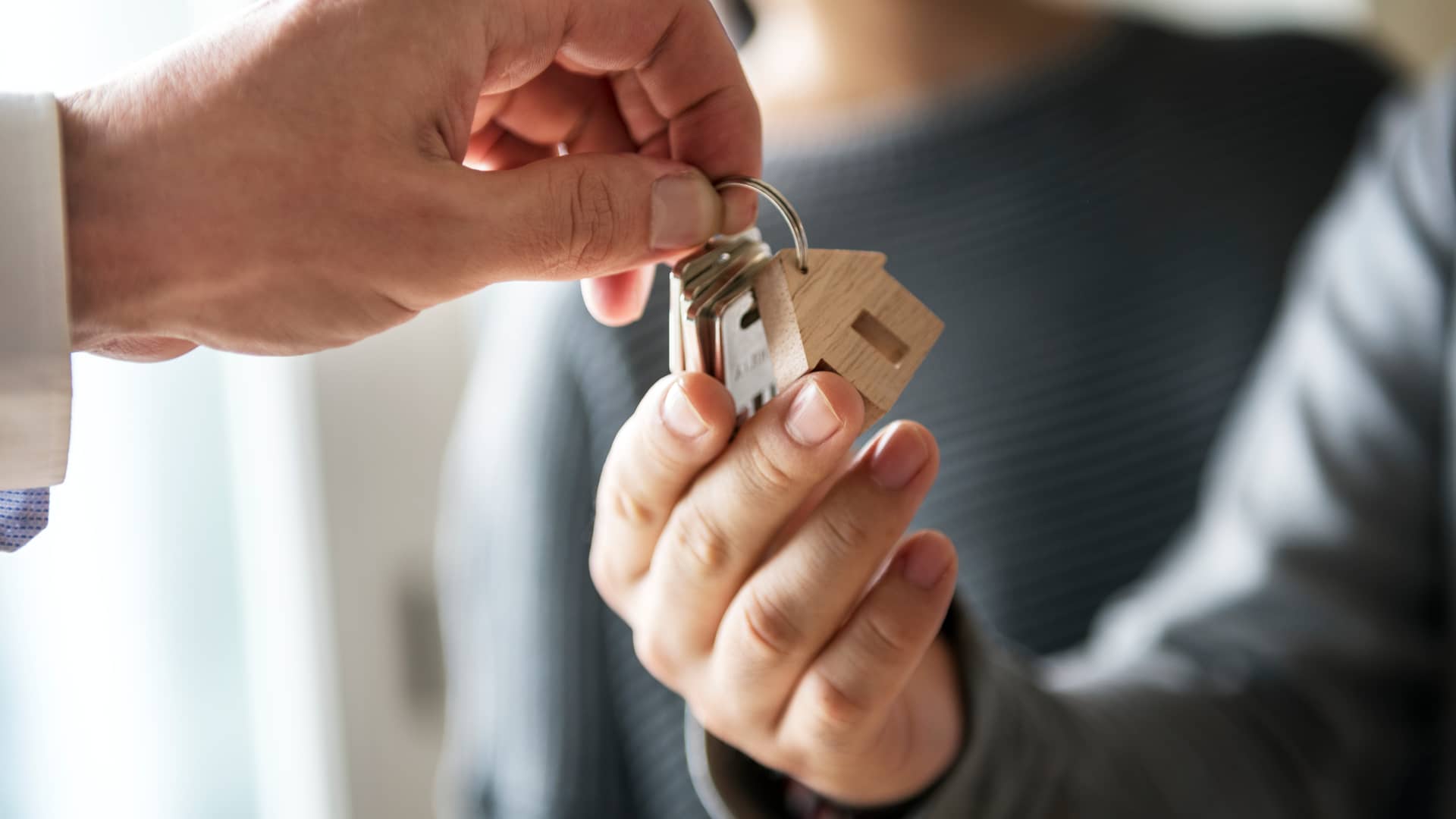 Hombre dando las llaves de su nueva vivienda a pareja la cual tendrá que pagar el impuesto de transmisiones patrimoniales