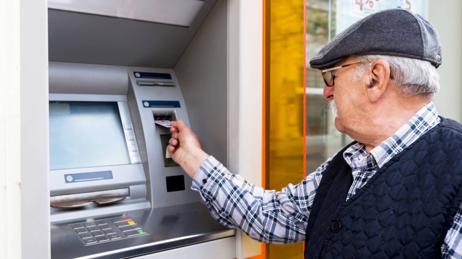 Hombre sacando dinero de cajero automático proveniente de su jubilación