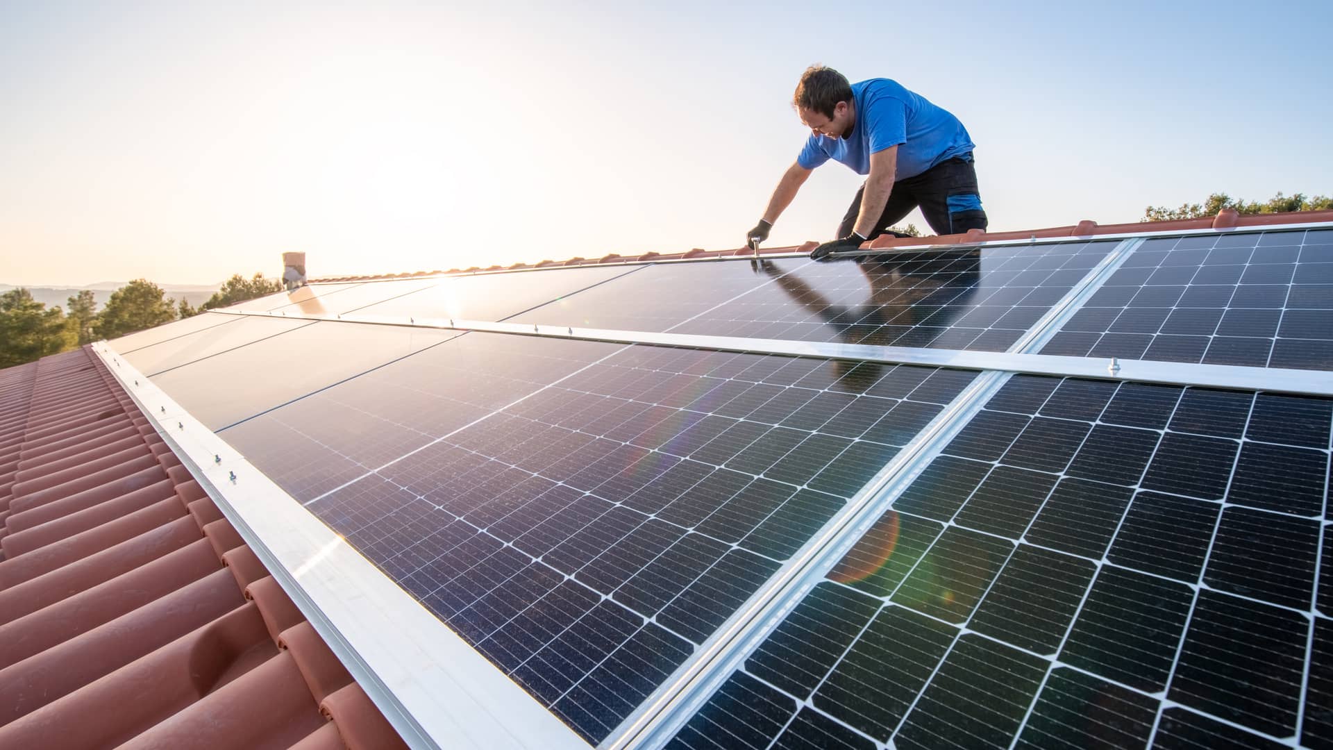 Hombre instalando paneles solares en su vivienda para hacerla aún más sostenible