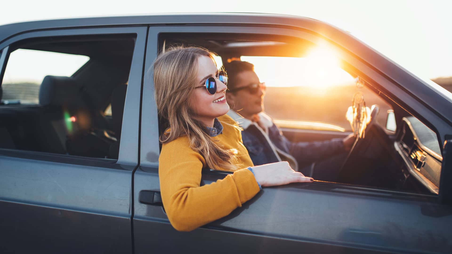 Mujer disfrutando de viaje con su pareja en su coche asegurado con banco pichincha