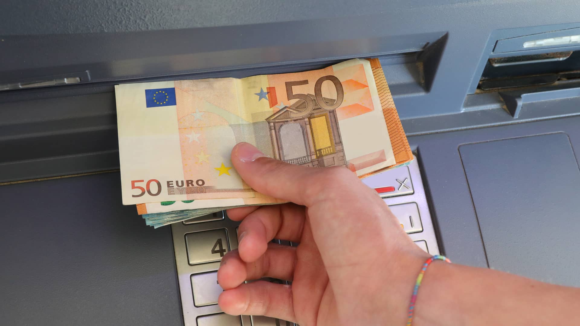 Persona sacando dinero de cajero automático de oficinas de bankia
