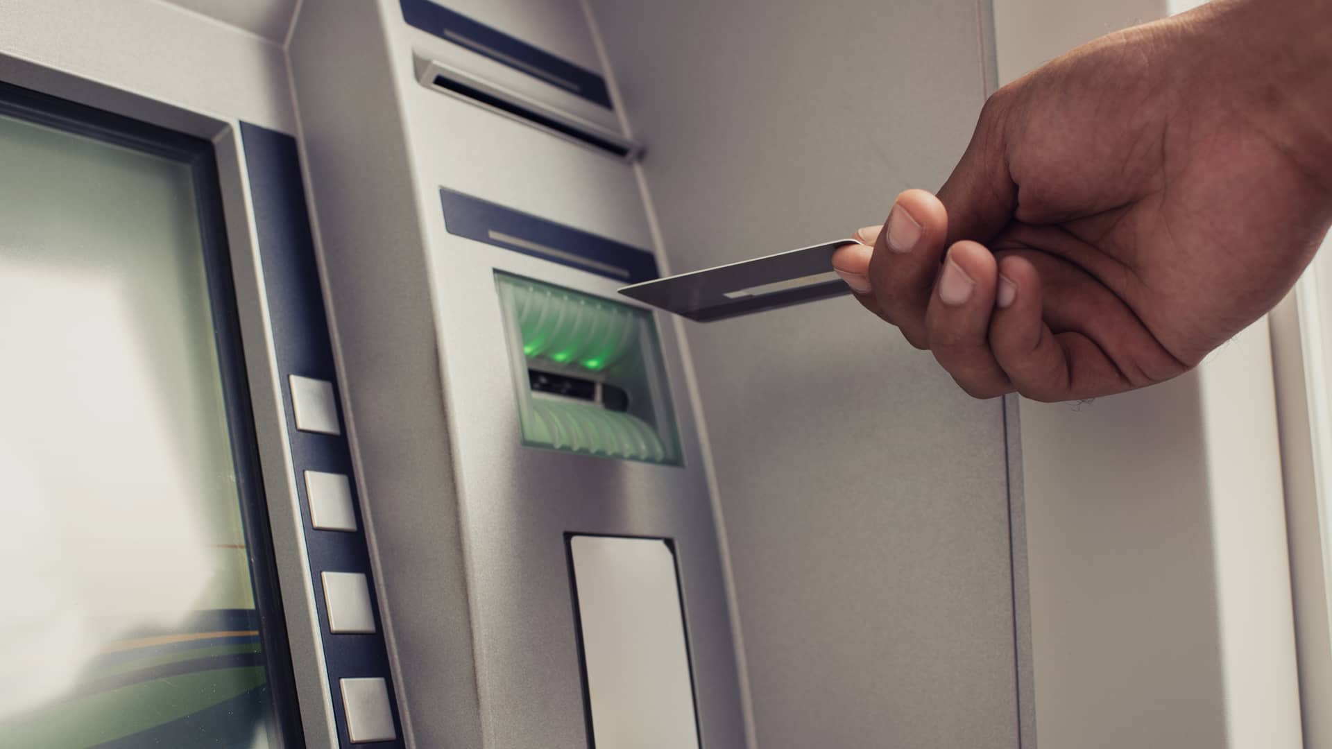 Persona introducinedo tarjeta de crédito en cajero automático de oficina cajamar