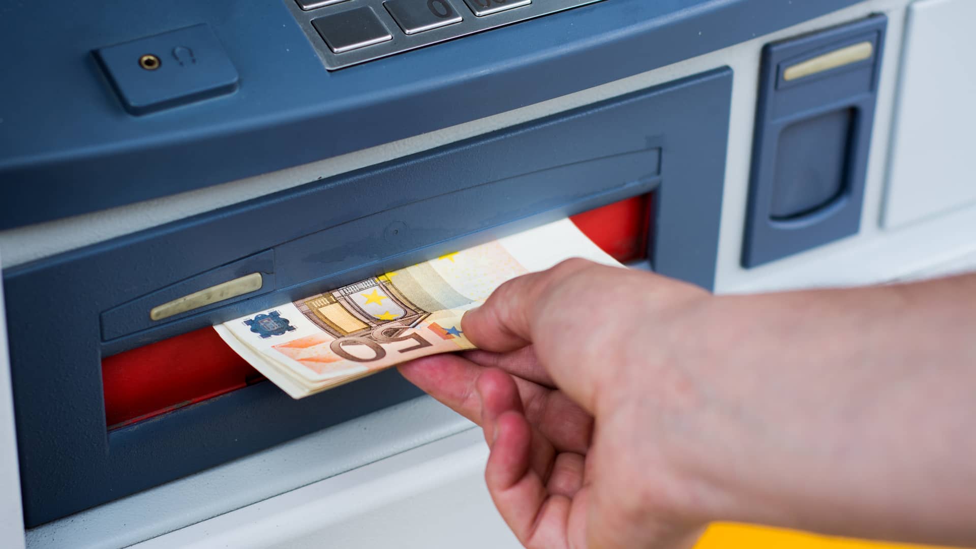 Persona sacando dinero de cajero automático sin tarjeta