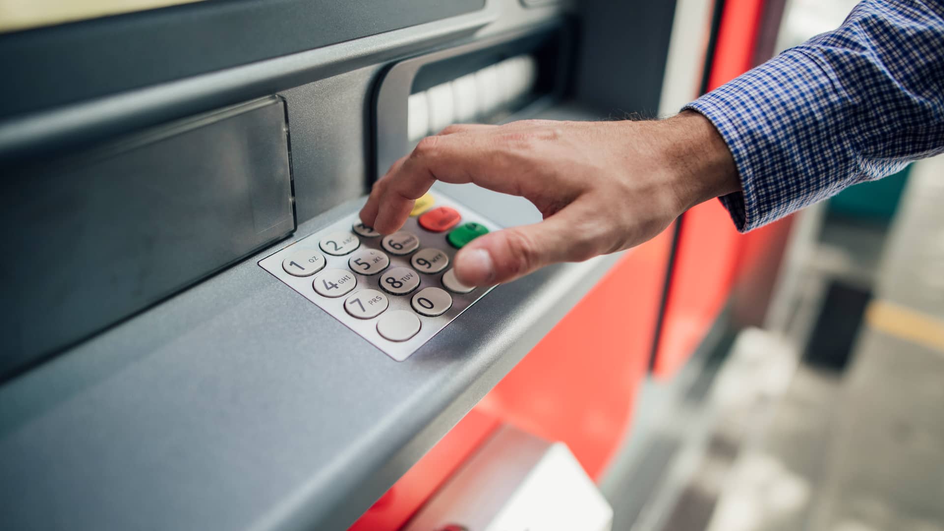 Hombre marcando número secreto en cajero automático para sacar dinero sín tarjeta