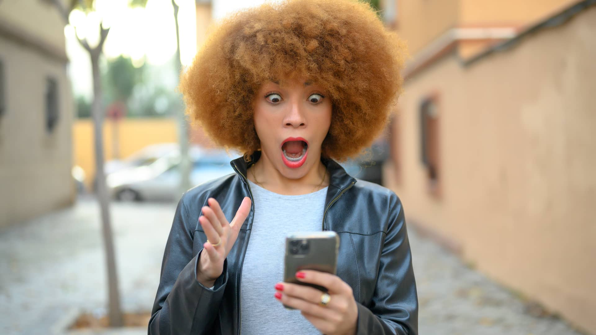 Mujer con cara de sorprendida al recibir en su smartphone un aviso de robo en su inversión