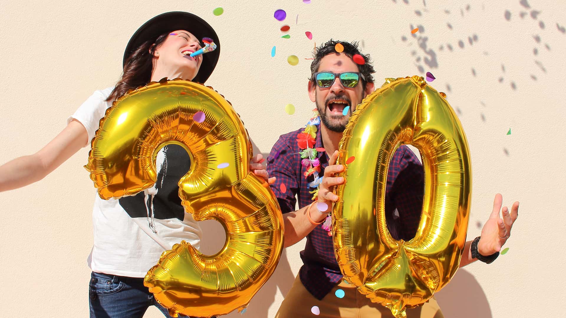 Pareja celebrando su cumpleaños con globos con forma de número 30, representando las hipotecas a 30 años