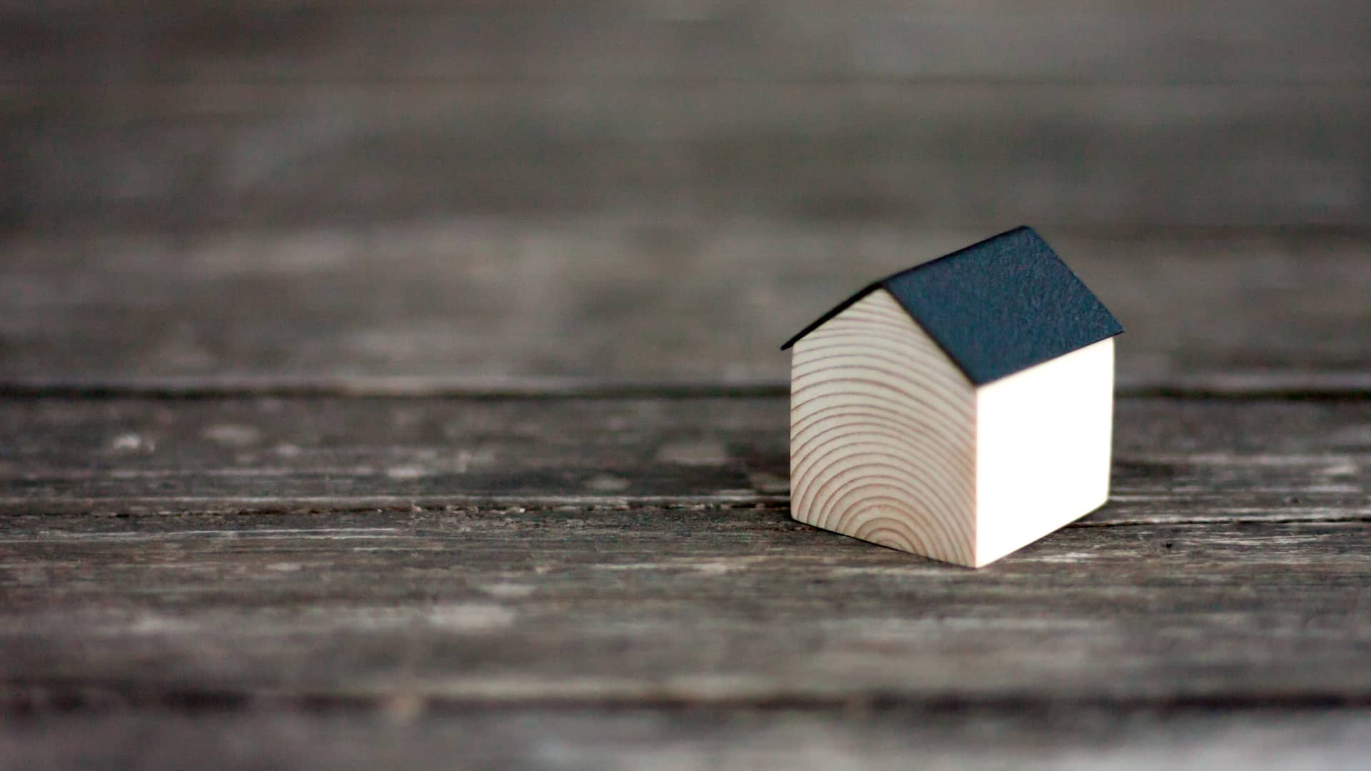 Casita de madera con el techo negro que representa un hogar con clausula suelo de caixabank