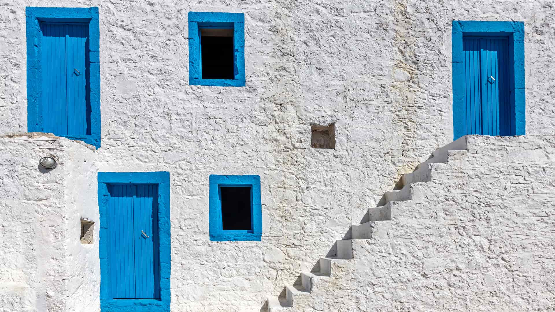 Fachada de una casa con puertas y ventanas azules que cuenta con una clausula suelo de cajamar