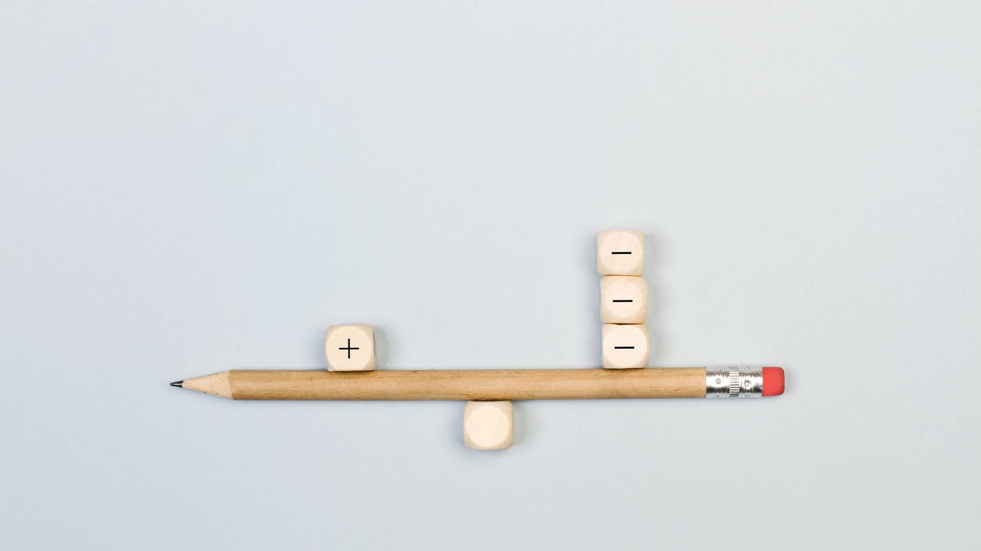 Balanza hecha con lápiz y dados con símbolo más y menos simboliza comisiones de hipotecas