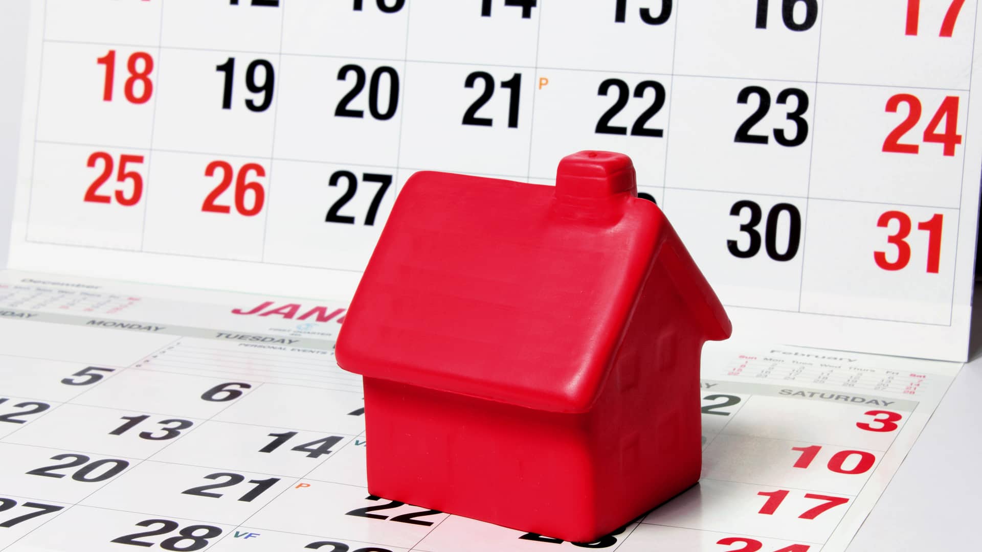 Casita roja de juguete sonbre un calendario para hablar de cuánto suelen tardar los bancos en conceder la hipoteca