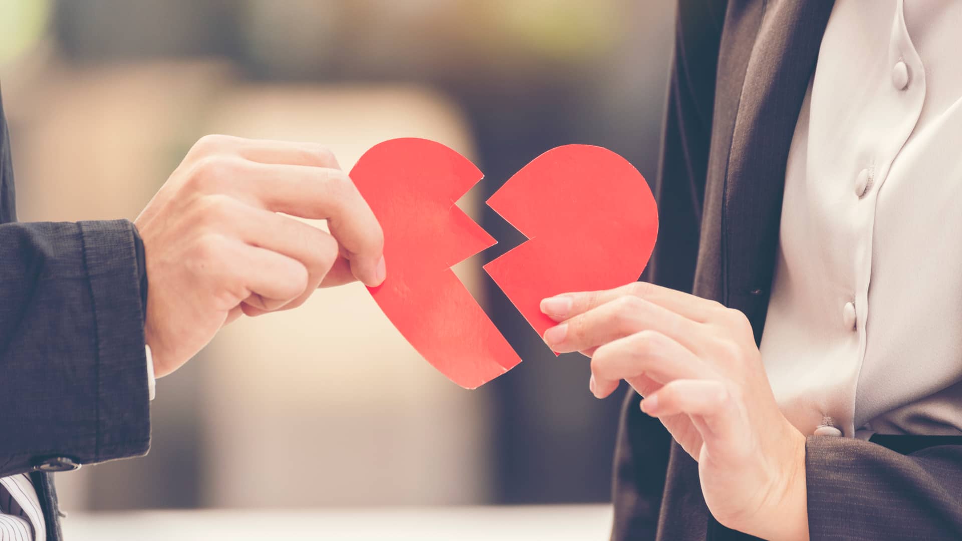 Dos personas sujetan los pedazos de un corazón roto de cartulina, las rupturas son una de las razones por las que se puede querer salir de una hipoteca compartida