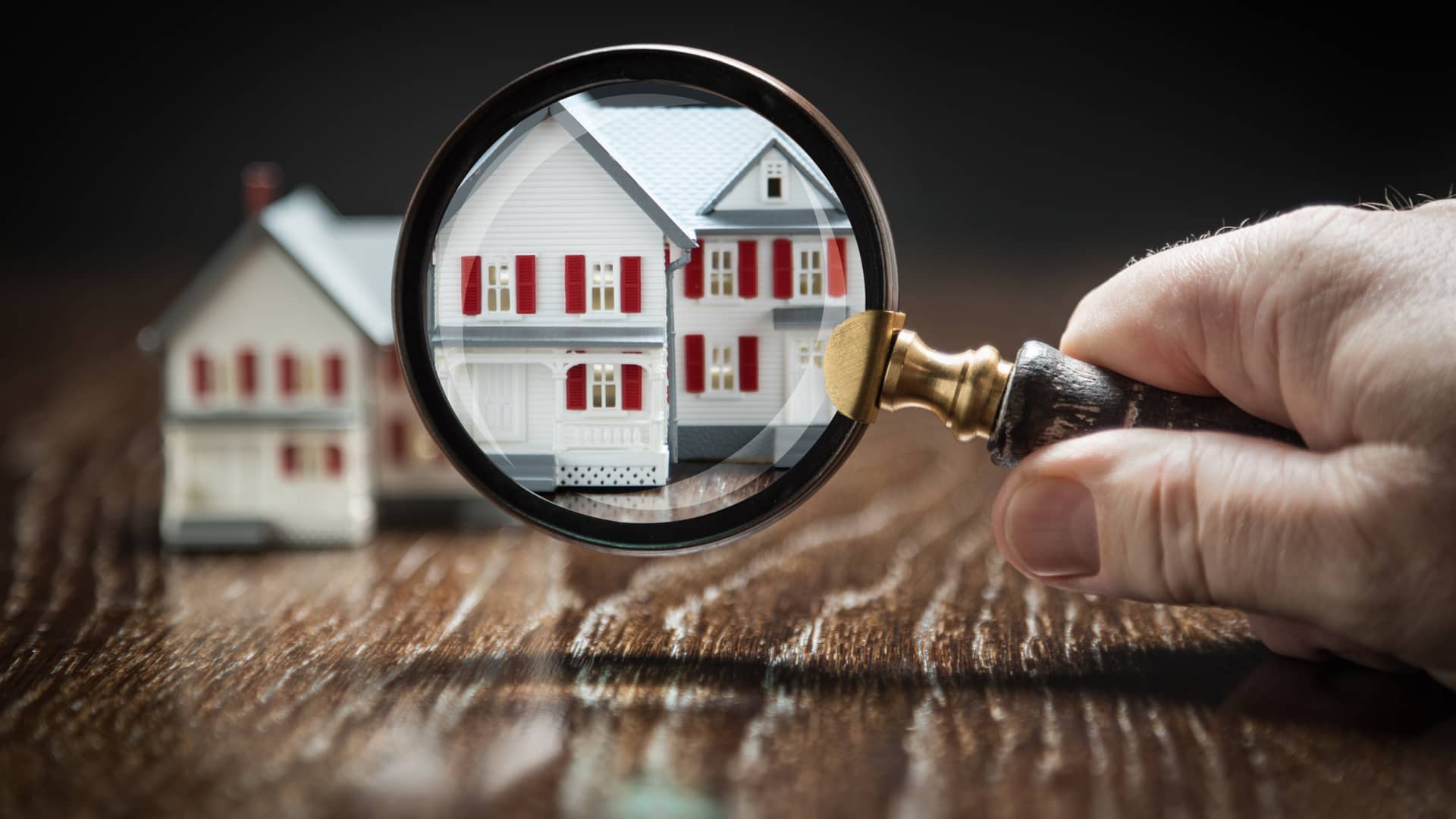 Persona mirando casitas con lupa simbolizando lo complicado de conseguir una hipoteca sin nómina